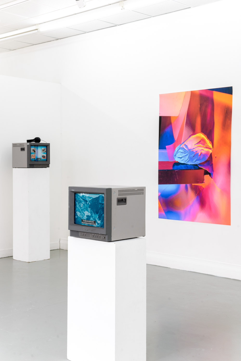 contemporary art installation in a white gallery with monitors on podiums and a frame on the wall by artist Stefano Conti